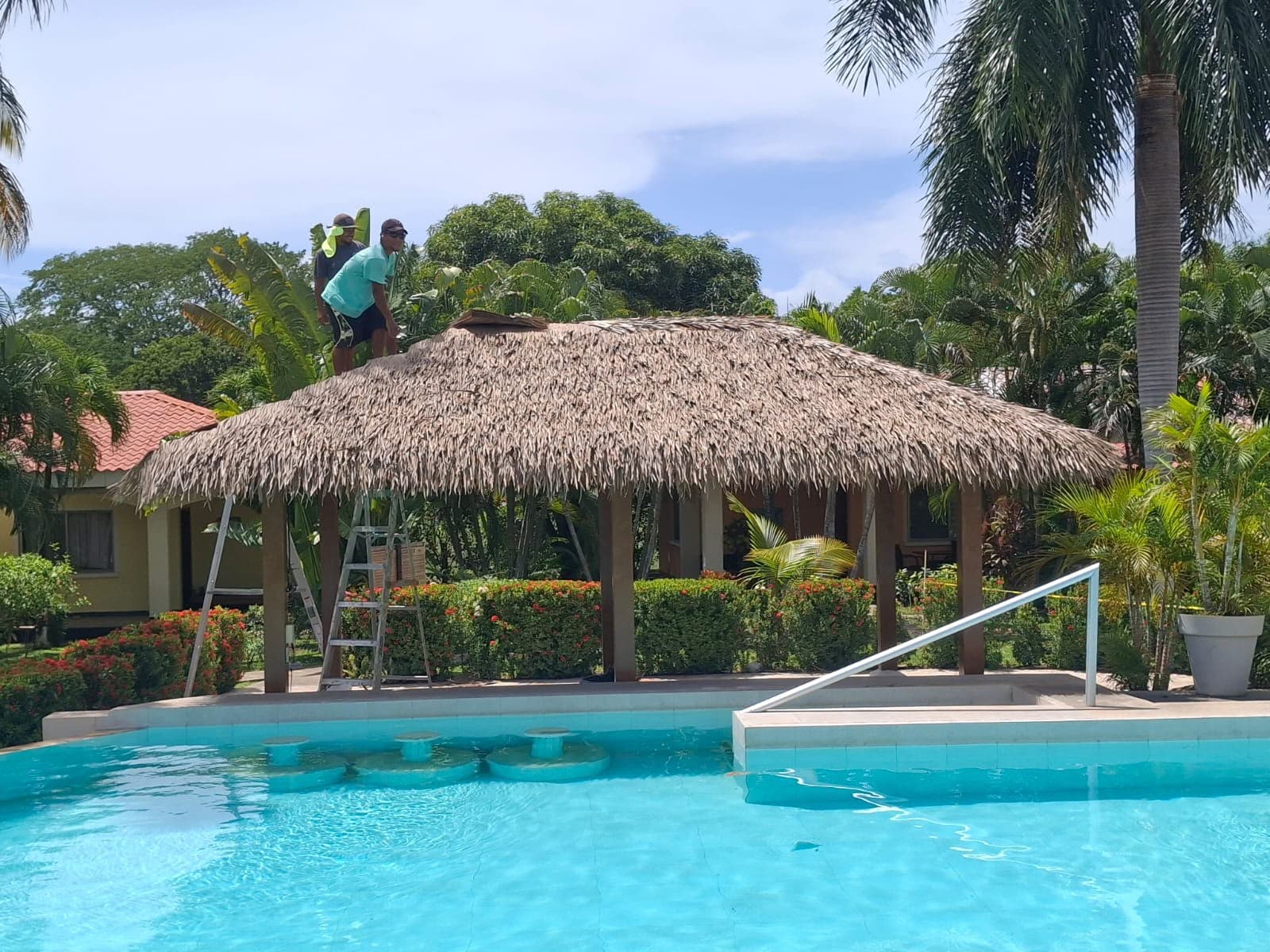 Rancho beside a pool with a synthetic thatch roof